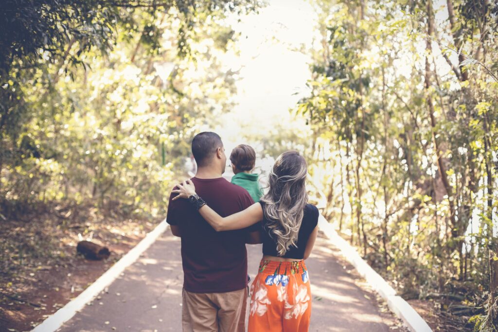 A family enjoying a leisurely walk on a sunny park trail, showcasing togetherness and love.